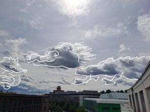 Eine fantasievolle Darstellung von Wolken am Himmel, die in Form von Tieren gezeichnet sind. Ein Drache und ein weiteres Tier scheinen miteinander zu interagieren. Im Hintergrund ist eine Stadtlandschaft mit modernen Gebäuden zu sehen.